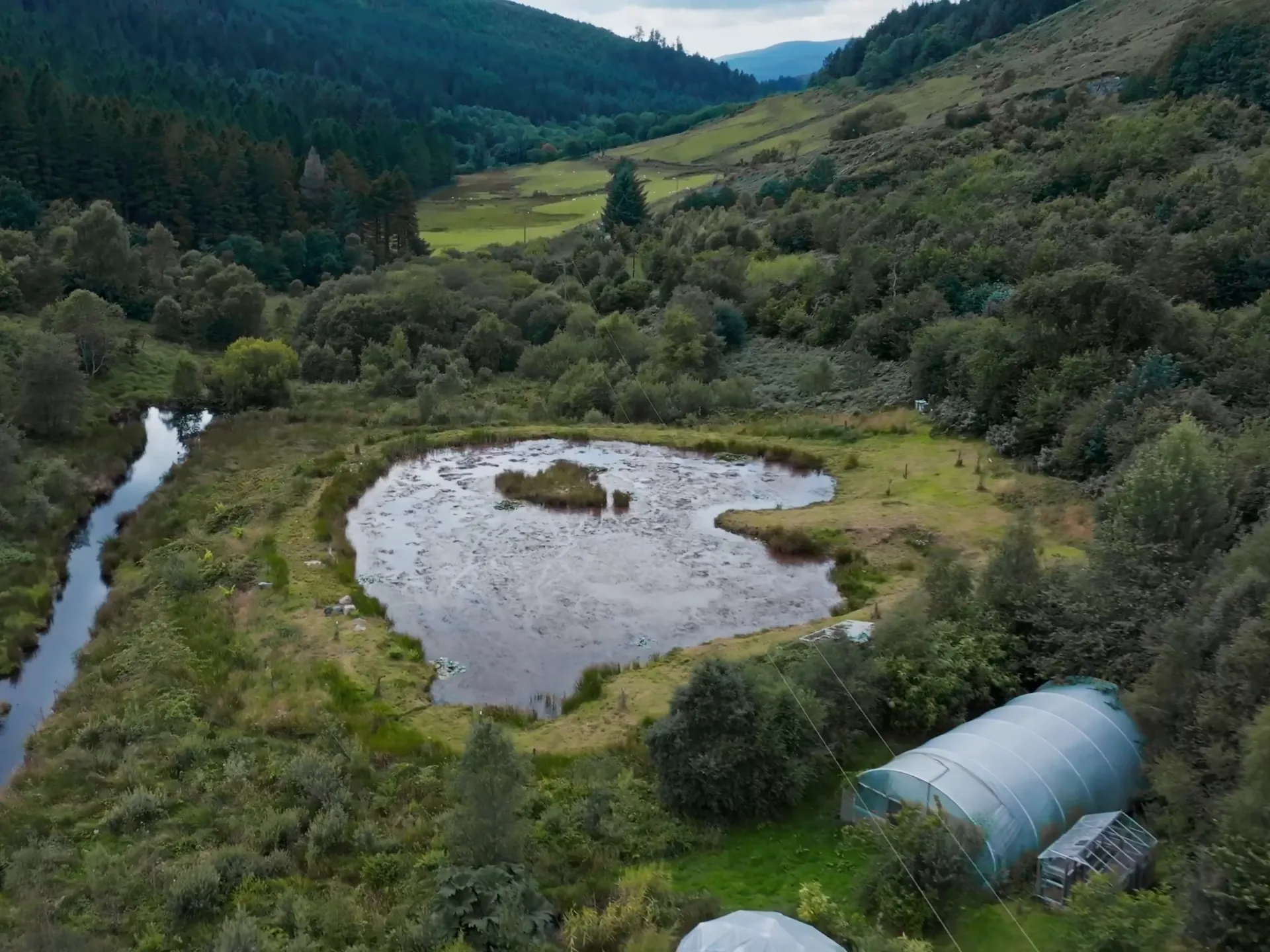 An aerial view of the valley, pond and polytunnel at Blaeneinion